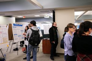 Attendees of the inaugural Thomas M. Carsey Graduate Student Symposium gather in the Davis Library Research Hub, where 20+ posters have been arranged in three rows.