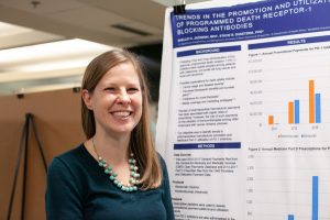 Student in front of a research poster, which features visible background, results, and methods sections.