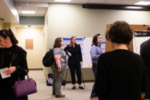 Attendees of the inaugural Thomas M. Carsey Graduate Student Symposium gather in the Davis Library Research Hub, where 20+ posters have been arranged in three rows.